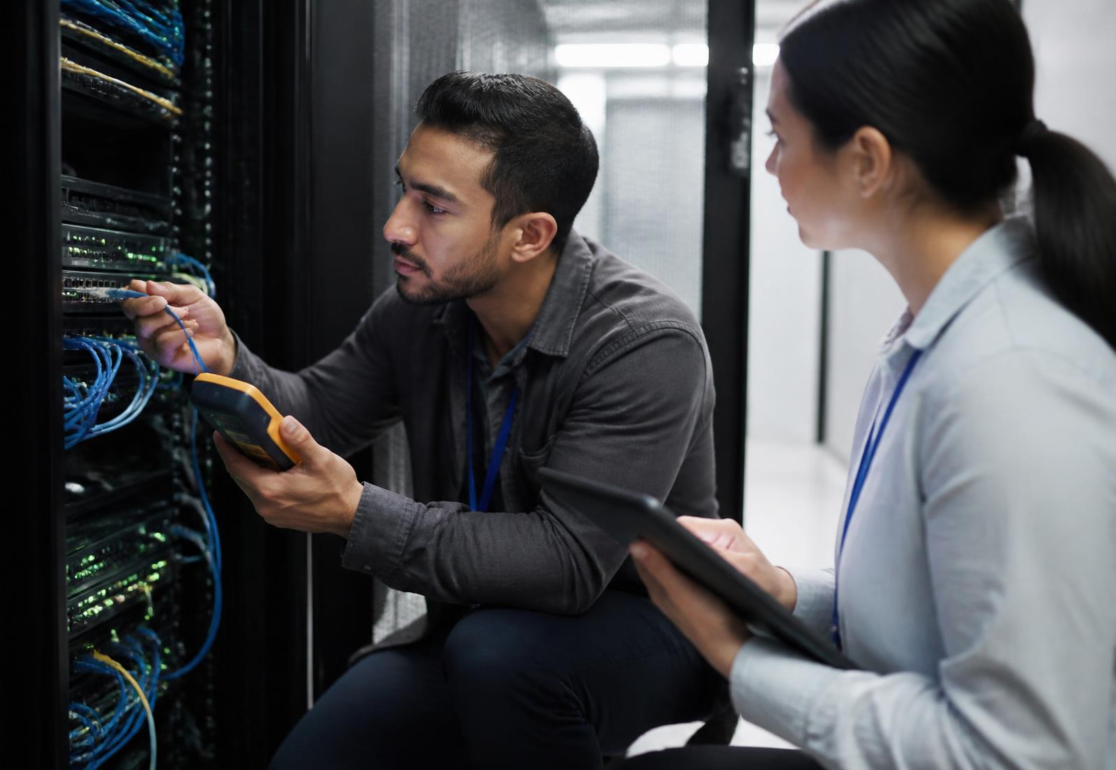 Field engineers testing structured cabling at a network rack and recording results